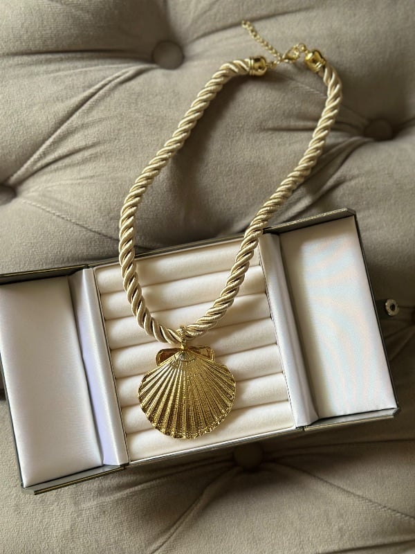 Collar de cordón con dije de concha
dorada