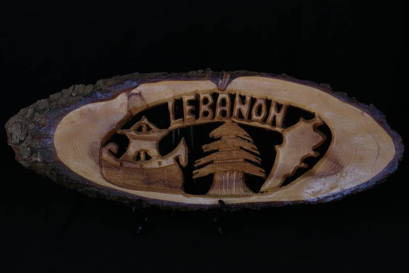 Hand-Carved Wooden Plaque – “LEBANON” with Cedar Tree and Heritage Motifs
لوحة خشبية محفورة يدويًا – "LEBANON" بتصميم أرز وشخصيات رمزية